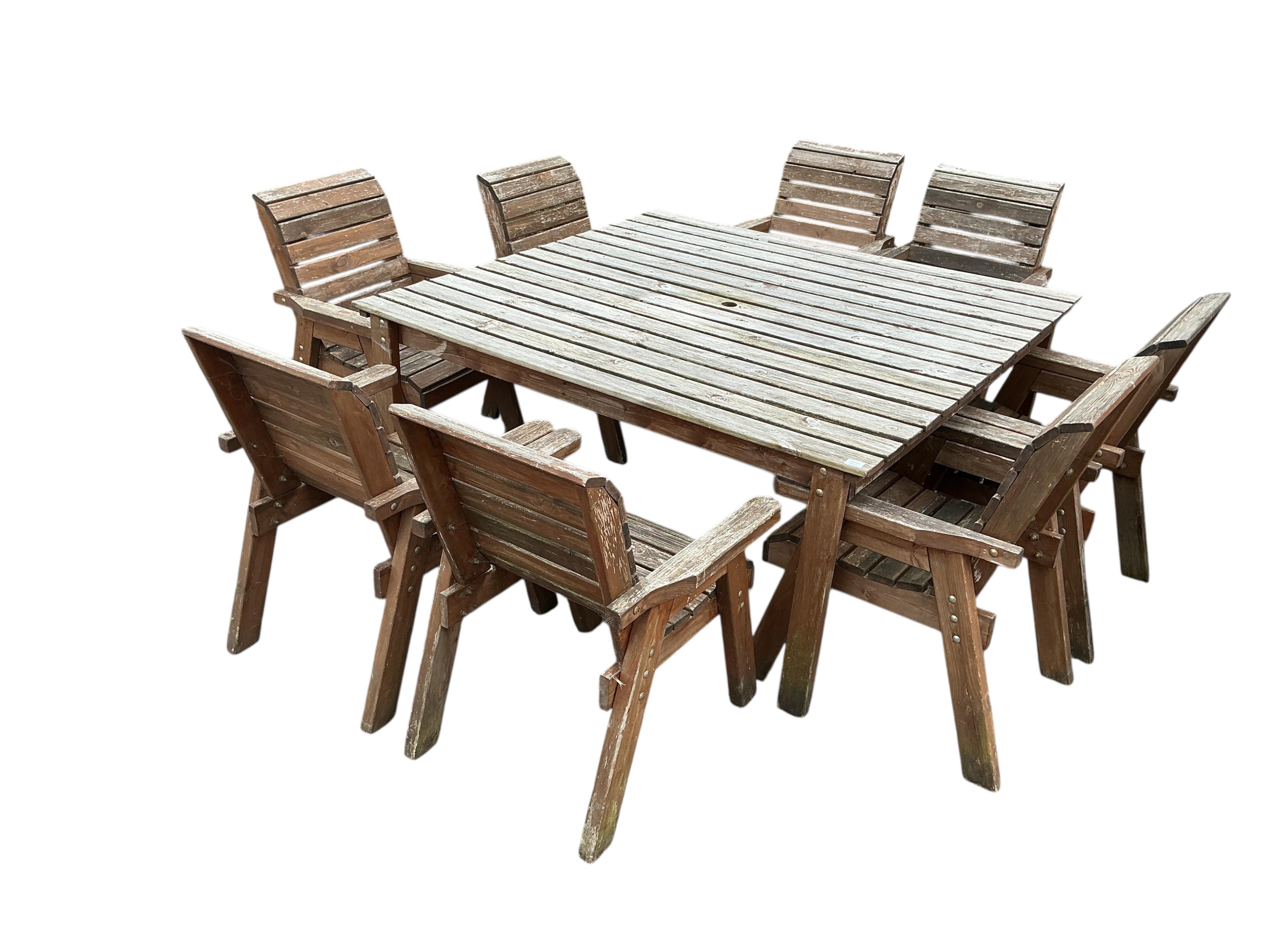 A large square weathered teak garden table, 161cm, height 80cm and set of eight matching slatted wood armchairs